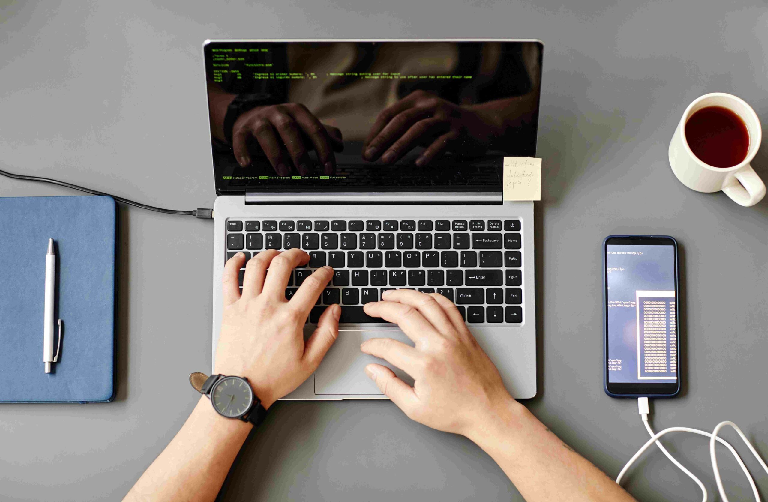 minimal-top-view-unrecognizable-man-using-laptop-writing-code-grey-workplace-desk (1)