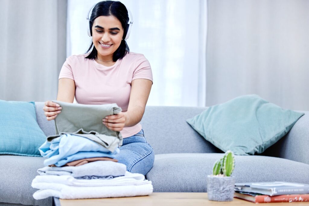 woman-headphones-laundry-clothes-home-neat-lounge-smiling-fabric-table-female-cleaner-house-sitting-sofa-folding-happy-listening-music-while-cleaning-apartment
