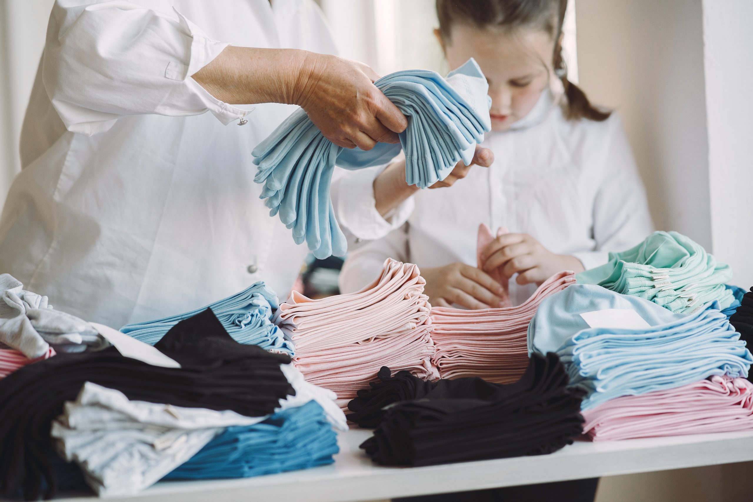 Grandmother with little granddaughter measure the fabric for sew